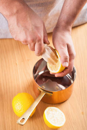 man squeezing lemon into a copper potの写真素材