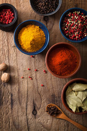 spices in bowls: pink and black pepper, paprika powder, curry, bay leafの写真素材