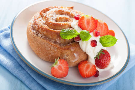 sweet cinnamon roll with cream and strawberry for breakfastの写真素材