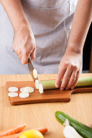 chef chopping leek in kitchen の写真素材