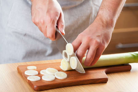 chef chopping leek in kitchen の写真素材