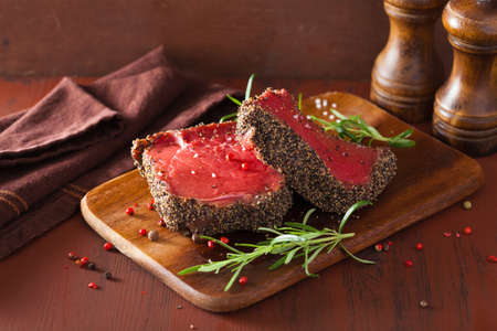 raw beef steak with spices and rosemary on wooden backgroundの写真素材
