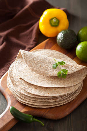 whole wheat tortillas on wooden board and vegetables