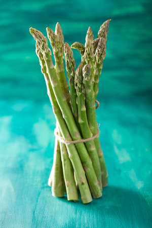 bunch of fresh asparagus on turquoise backgroundの写真素材