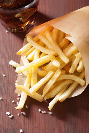 french fries and cola over rustic background
