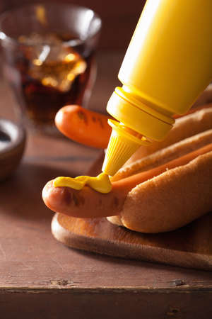 adding mustard to grilled hot dogの写真素材