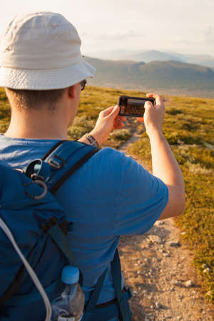 hiker taking photo of mountain landscape with smartphoneの写真素材