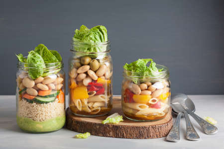 vegan couscous and pasta salad in mason jars with vegetables beans
