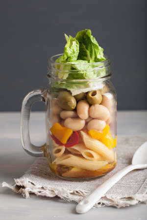 vegan pasta salad in mason jars with vegetables beans olivesの写真素材