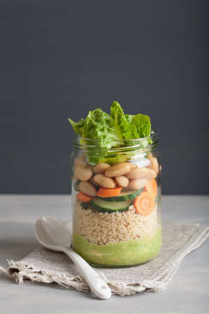 vegan couscous salad in mason jar with beans cucumber carrot and avocado dressingの写真素材