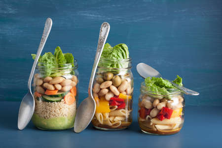 vegan couscous and pasta salad in mason jars with vegetables beansの写真素材