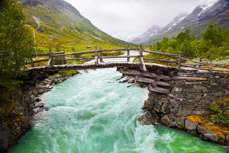 small walk bridge over green river in Norwayの写真素材