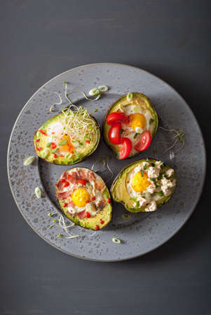 eggs baked in avocado with bacon, cheese, tomato and alfalfa sproutsの写真素材
