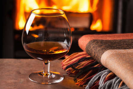 a glass of cognac in front of fireplaceの写真素材