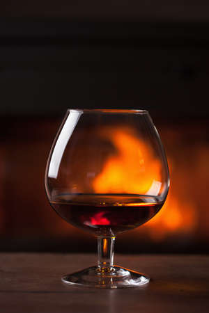 a glass of cognac in front of fireplaceの写真素材