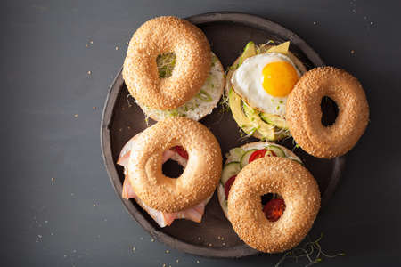 variety of sandwiches on bagels: egg, avocado, ham, tomato, soft cheese, alfalfa sproutsの写真素材