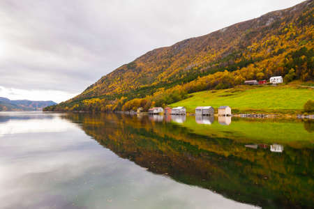 autumn rural landscape with houses near river, Norwayの写真素材
