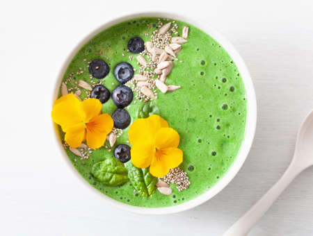 green spinach smoothie bowl with blueberry, chia seed and edible pansy flowersの写真素材