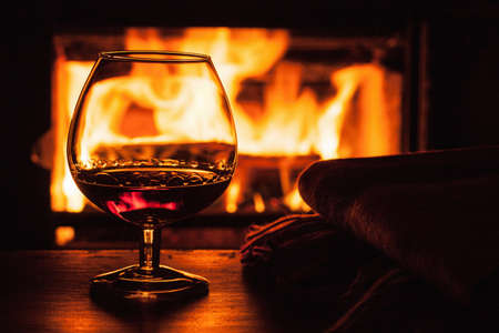 glass of cognac in front of fireplaceの写真素材