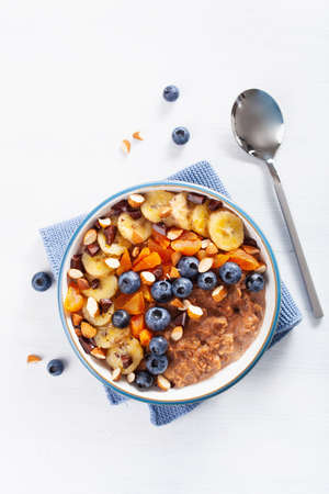 Chocolate oatmeal porridge with blueberry, nuts, banana, dried apricot for healthy breakfast. Top viewの写真素材