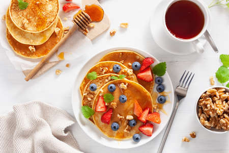Pancakes with blueberry strawberry honey and nuts for breakfastの写真素材