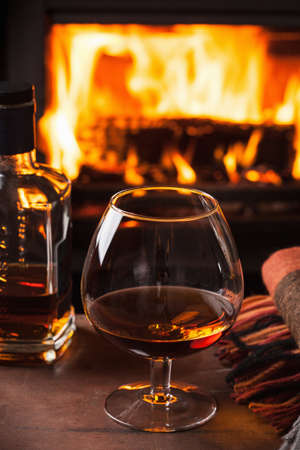 glass of cognac in front of fireplace