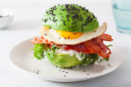 Keto paleo diet avocado breakfast burger with bacon, egg, tomatoの写真素材