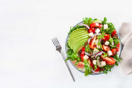 greek style avocado tomato salad with feta cheese, olives, cucumber, onion, lettuceの写真素材