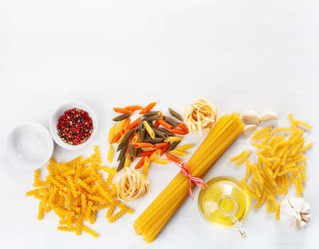 assorted raw pasta flat lay on white. spaghetti fusilli penne tagliatelle girandoleの写真素材