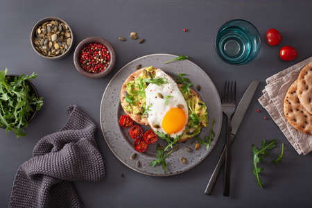 breakfast avocado sandwich with fried egg and tomatoesの写真素材