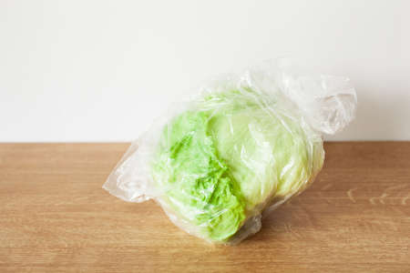 iceberg lettuce vegetable in plastic bag. single use plastic packaging issueの写真素材