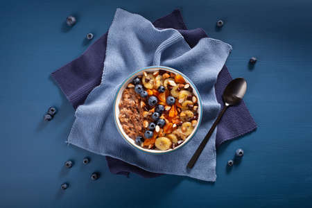 chocolate oatmeal porridge with blueberry, nuts, banana, dried apricot for healthy breakfast. Top viewの写真素材