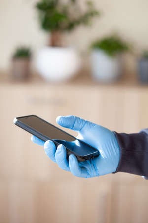 man hands in gloves using smartphone, preventing germs coronavirus bacteria