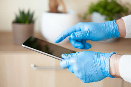 man hands in gloves using tablet computer, preventing germs coronavirus bacteriaの写真素材