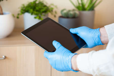 man hands in gloves using tablet computer, preventing germs coronavirus bacteriaの写真素材