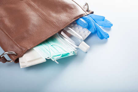 protective medical mask, sanitizer gel and gloves in pink bag. protective measures against virus, bacteriaの写真素材