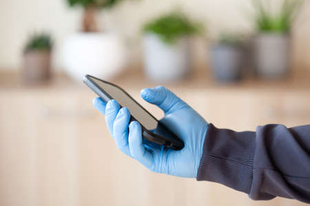 man hands in gloves using smartphone, preventing germs coronavirus bacteriaの写真素材
