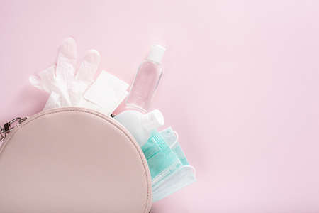 protective medical mask, sanitizer gel and gloves in pink bag. protective measures against virus, bacteriaの写真素材