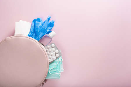 protective medical mask, sanitizer gel and gloves in pink bag. protective measures against virus, bacteriaの写真素材