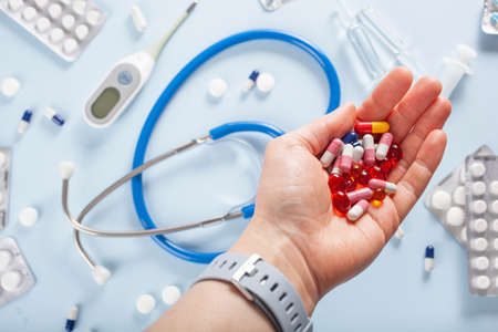Hand holding pills on blueの写真素材