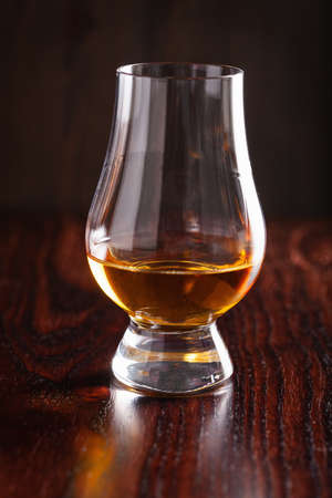 glass of whisky spirit brandy on dark brown background