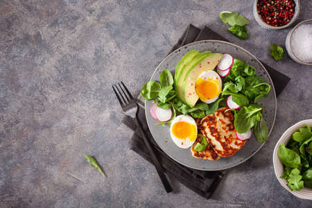healthy keto paleo diet breakfast: boiled egg, avocado, halloumi cheese, salad leavesの写真素材