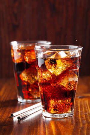 glass of cold cola soft drink with ice on wooden backgroundの写真素材