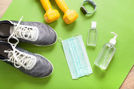 protective medical mask sanitizer gel gloves. fitness training sneakers dumbbell and protective measures against virus, bacteriaの写真素材