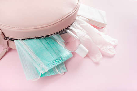 protective medical mask, sanitizer gel and gloves in pink bag. protective measures against virus, bacteriaの写真素材