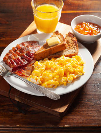 traditional scrambled egg breakfast with bacon and toastの写真素材
