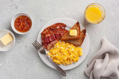 traditional scrambled egg breakfast with bacon and toastの写真素材