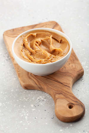 smooth peanut butter in bowl on gray background