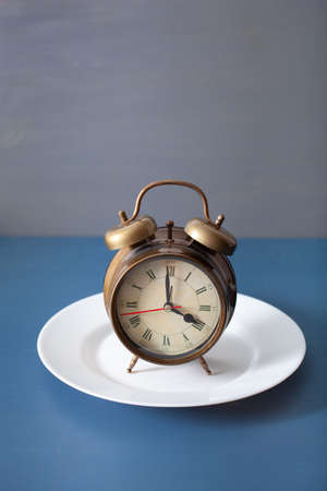concept of intermittent fasting, ketogenic diet, weight loss. alarmclock on a plate