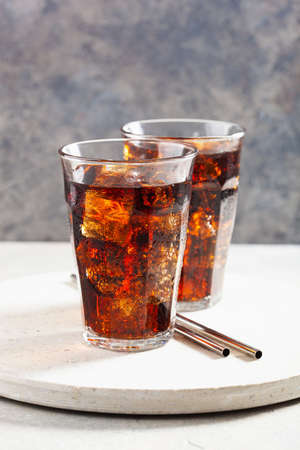 glass of cold cola soft drink with ice on wooden backgroundの写真素材
